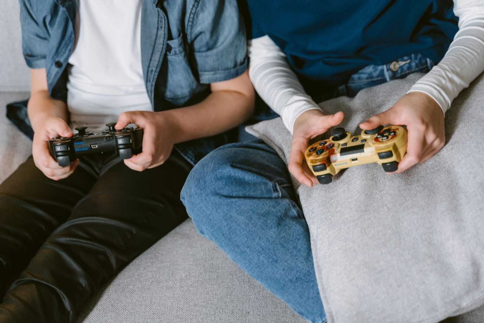 Two teenagers absorbed in console gaming indoors, focused on controllers.